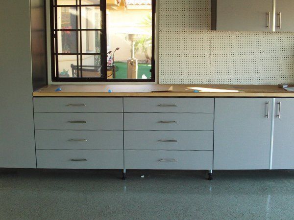 A kitchen with white cabinets and drawers and a window