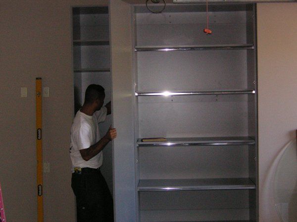 A man is measuring a shelf with a yellow level