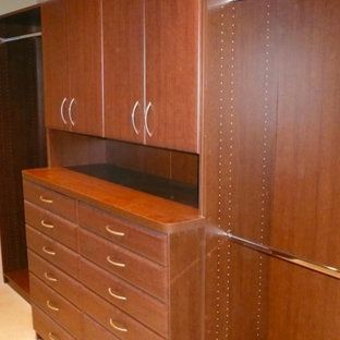 A walk in closet with lots of wooden cabinets and drawers