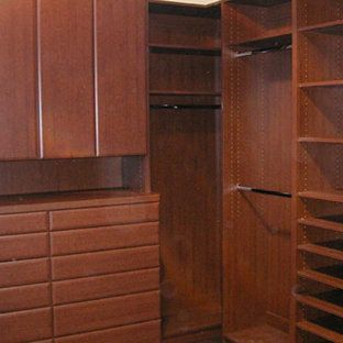 A walk in closet with lots of wooden cabinets and shelves.