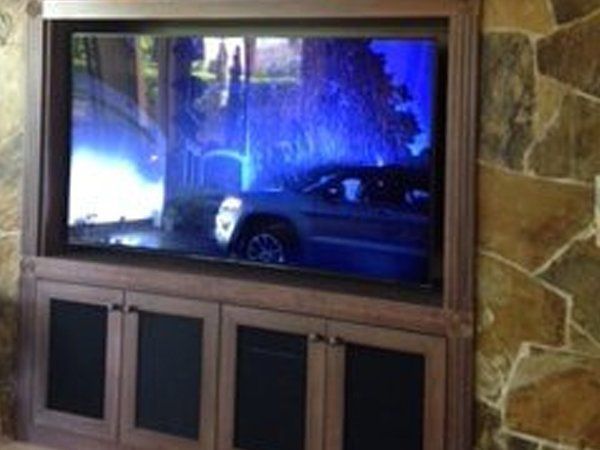 A large flat screen tv is sitting on top of a wooden entertainment center.