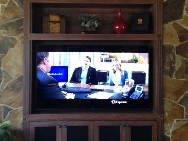 A tv screen shows a man talking to two women
