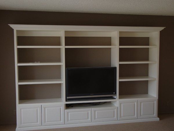 A white entertainment center with a flat screen tv on top