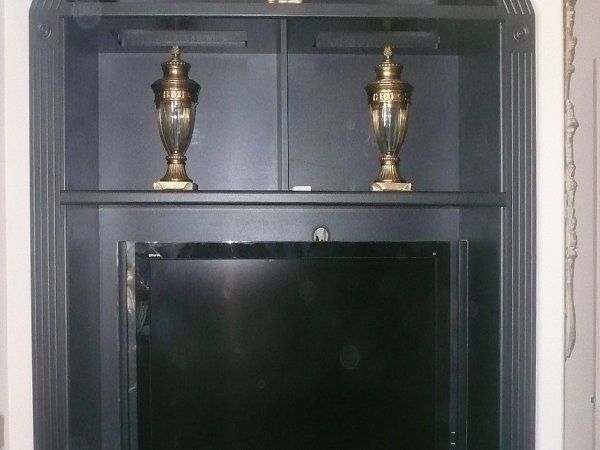 A television is sitting on top of a shelf with two vases on it.