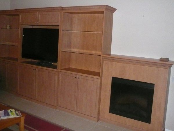 A wooden entertainment center with a fireplace and a flat screen tv