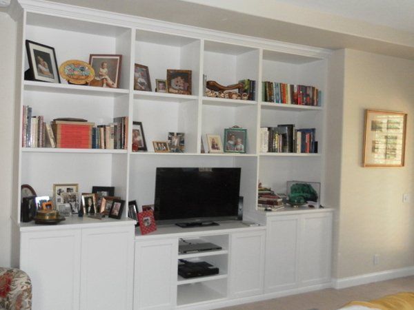 A living room with white shelves and a flat screen tv
