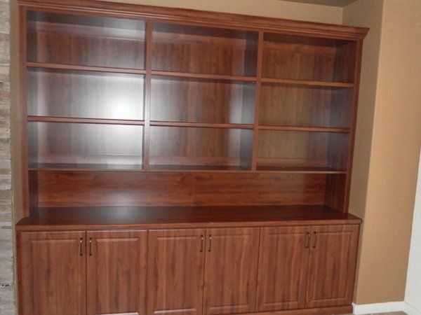 A large wooden bookcase with lots of shelves and cabinets