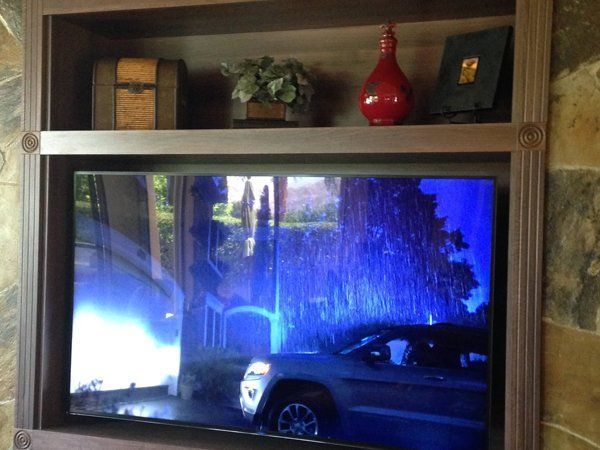 A car is parked in front of a tree on a television screen.