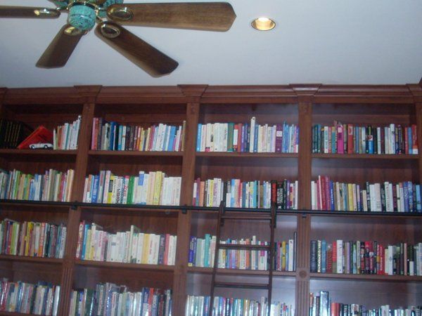 A library with a ceiling fan and lots of books