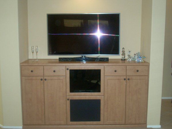 A flat screen tv is mounted above a wooden entertainment center
