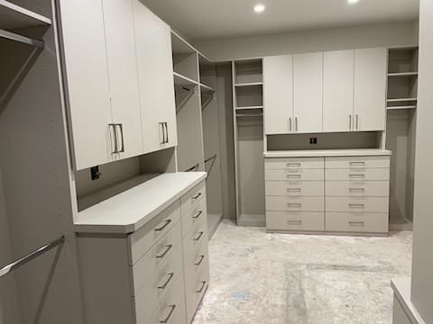 A walk in closet with lots of white cabinets and drawers.