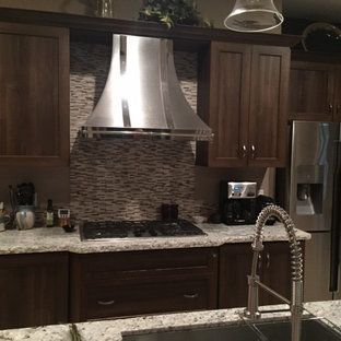 A kitchen with a stove , sink , refrigerator and hood.