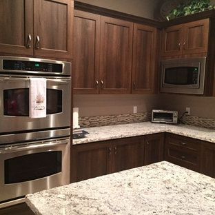 A kitchen with stainless steel appliances , granite counter tops , and wooden cabinets.