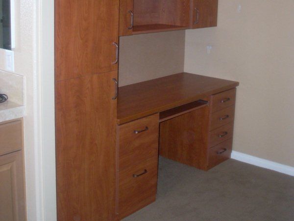 A wooden desk in a room next to a cabinet