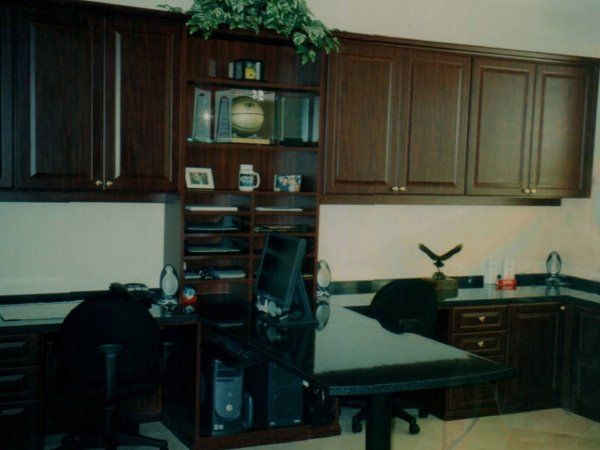A corner of a room with a desk and chairs