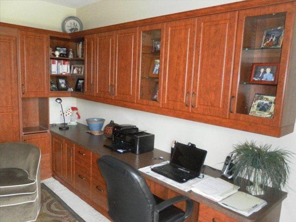 A home office with wooden cabinets and a desk with a laptop on it