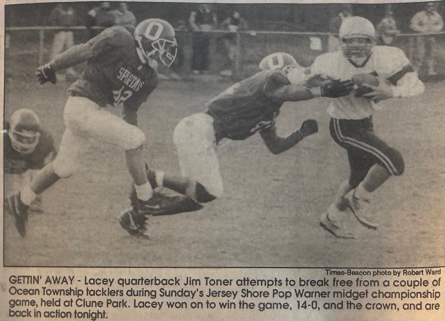 Football game action: Quarterback attempts to break tackles. Players in jerseys on a field.