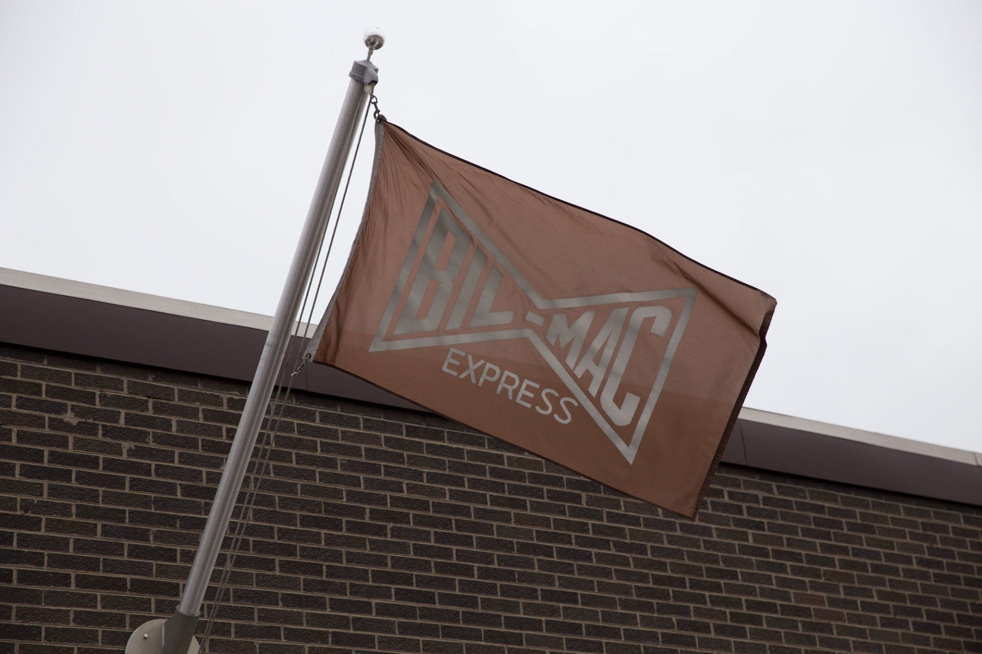 A brown flag with the word express on it is flying in front of a brick building.