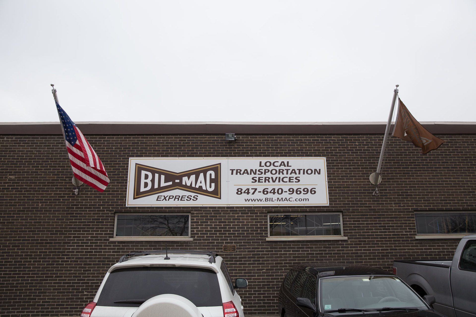 Two cars are parked in front of a building that says bil-mac