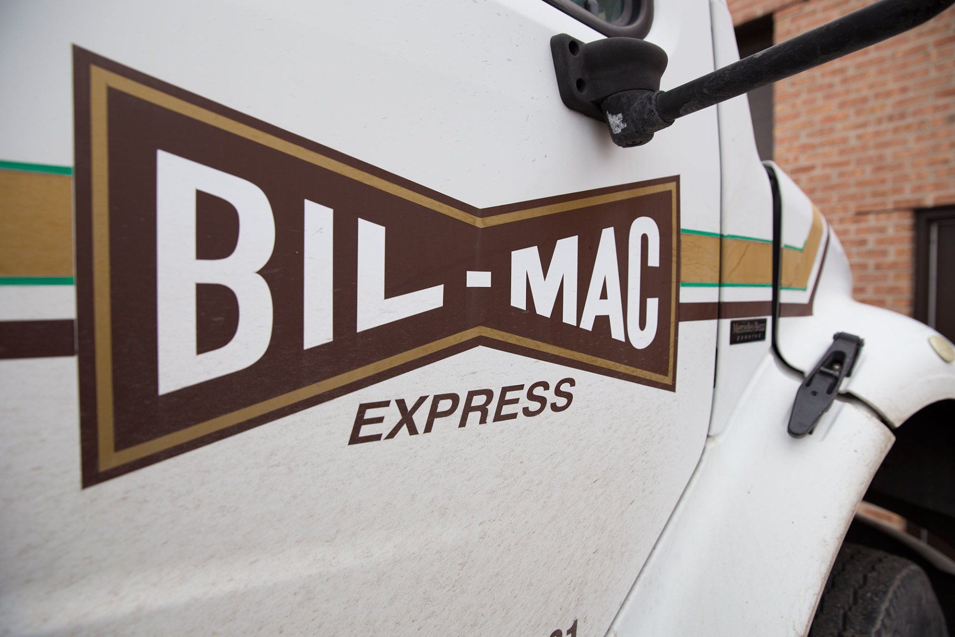 A bil-mac express truck is parked in front of a brick building