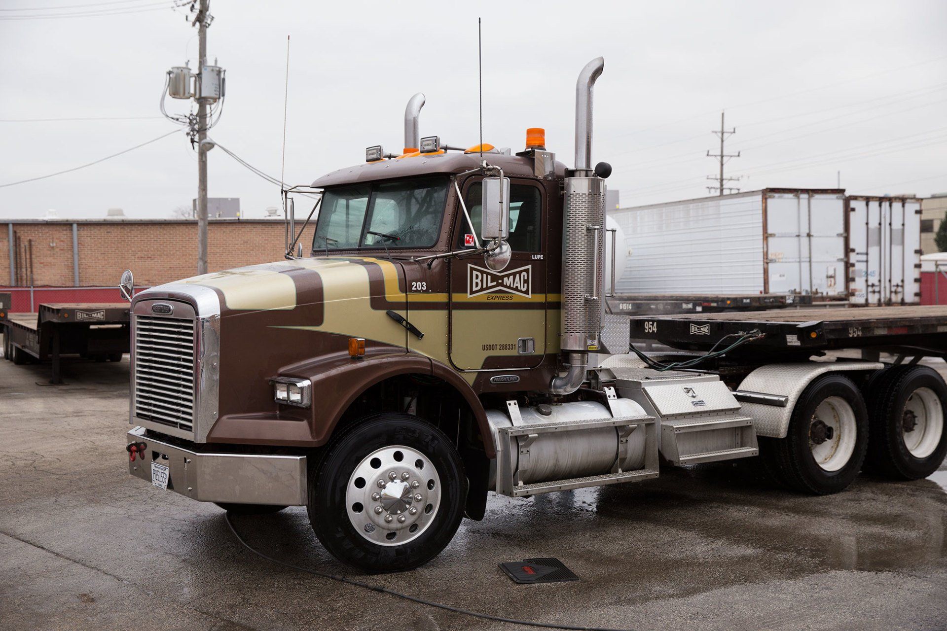A semi truck with a flatbed trailer attached to it is parked in a parking lot.