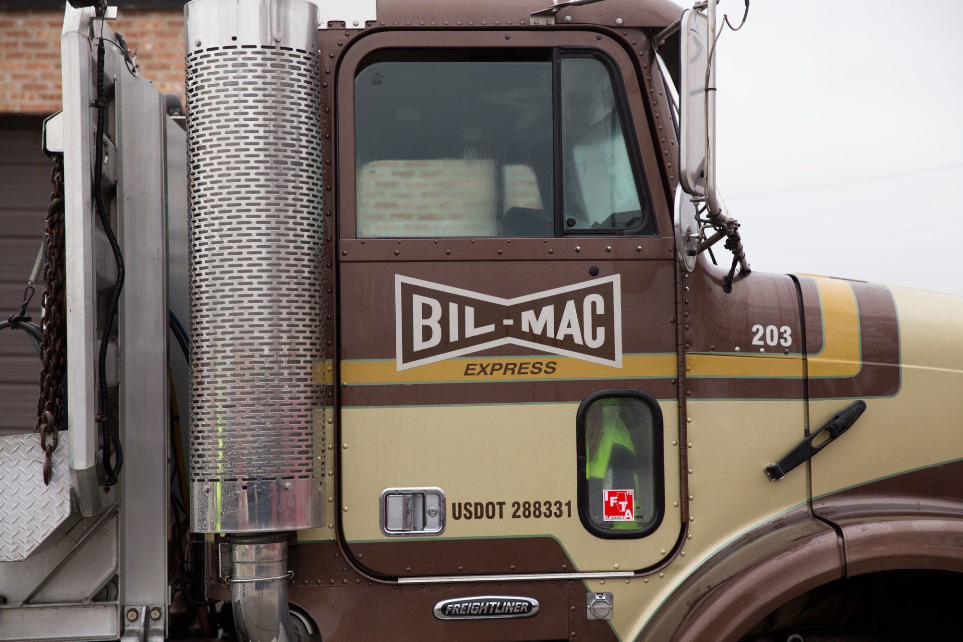 A bil-mac truck is parked in front of a garage