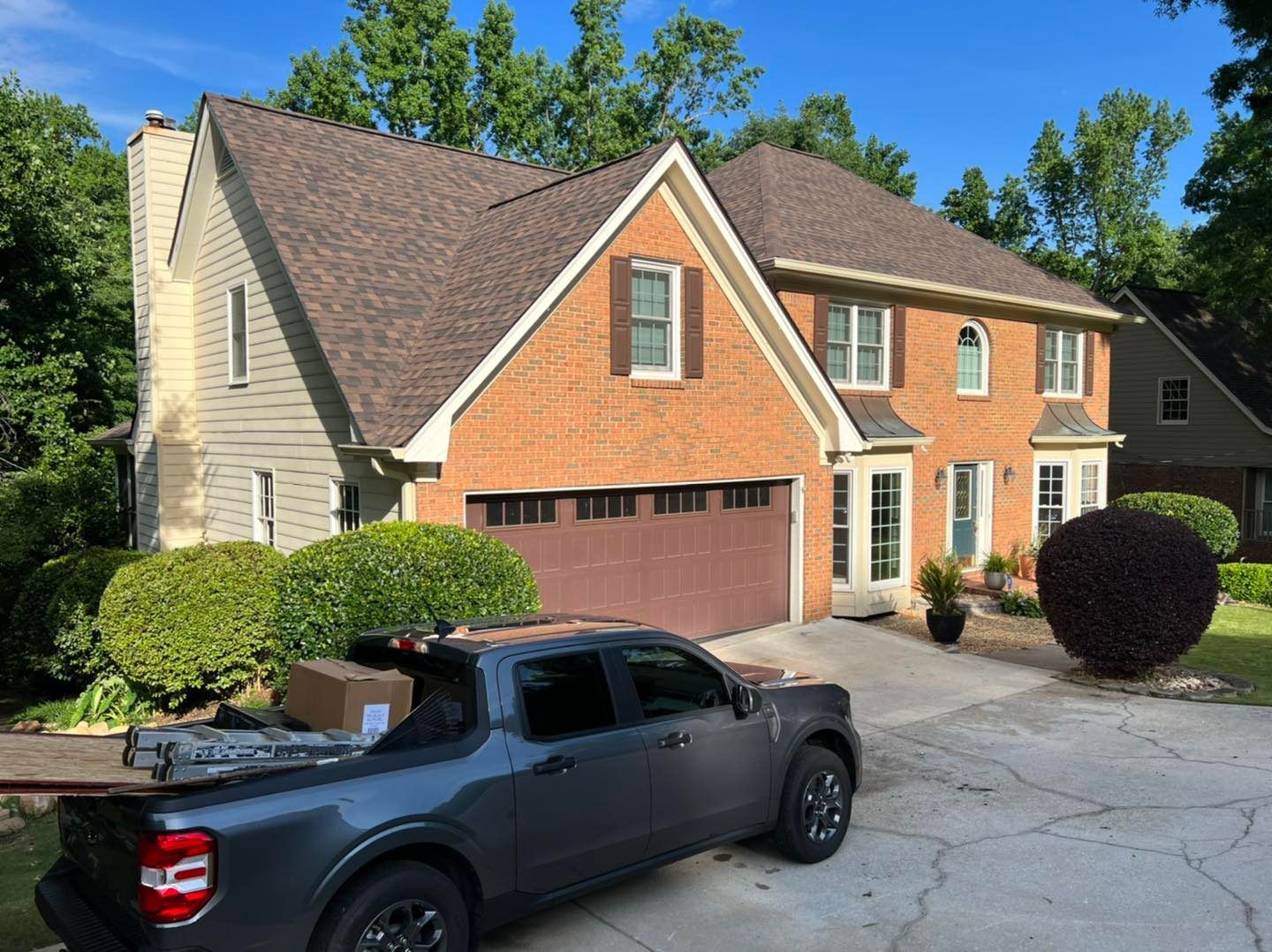 Two-story brick house with brown roof and garage that needs roof replacement 