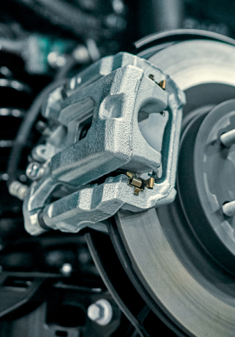 Close-up of a car brake caliper gripping a rotating brake disc.