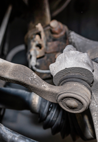 Close-up of a dusty car suspension control arm and ball joint with brake components visible