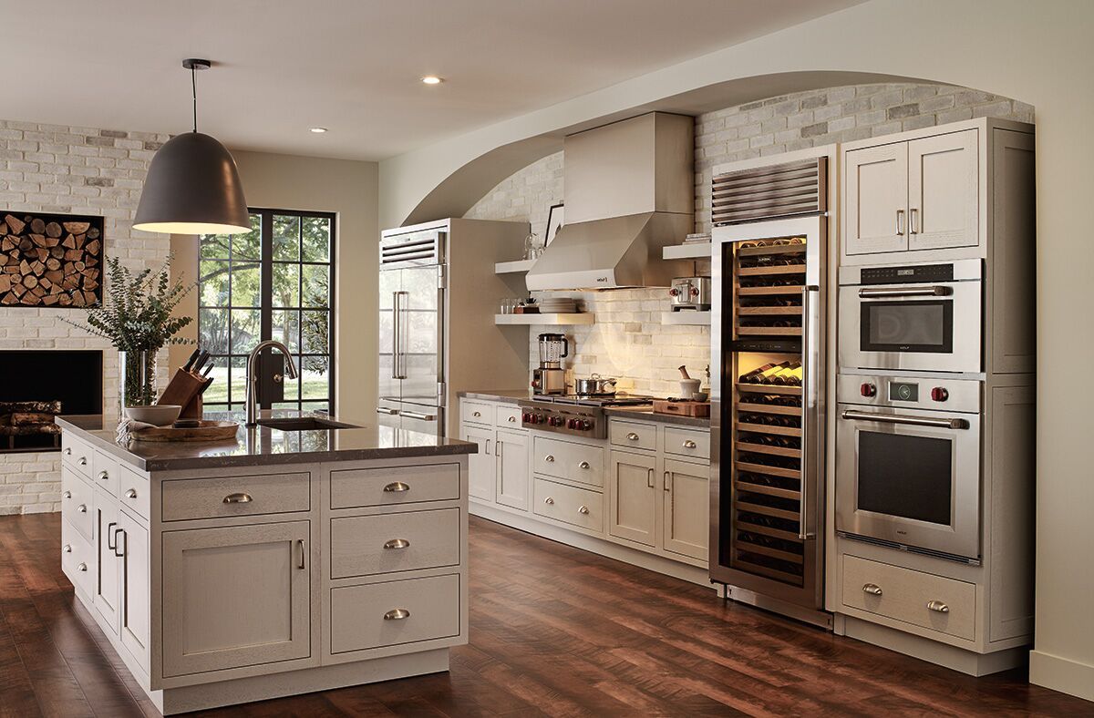 A kitchen with white cabinets , stainless steel appliances and a large island.