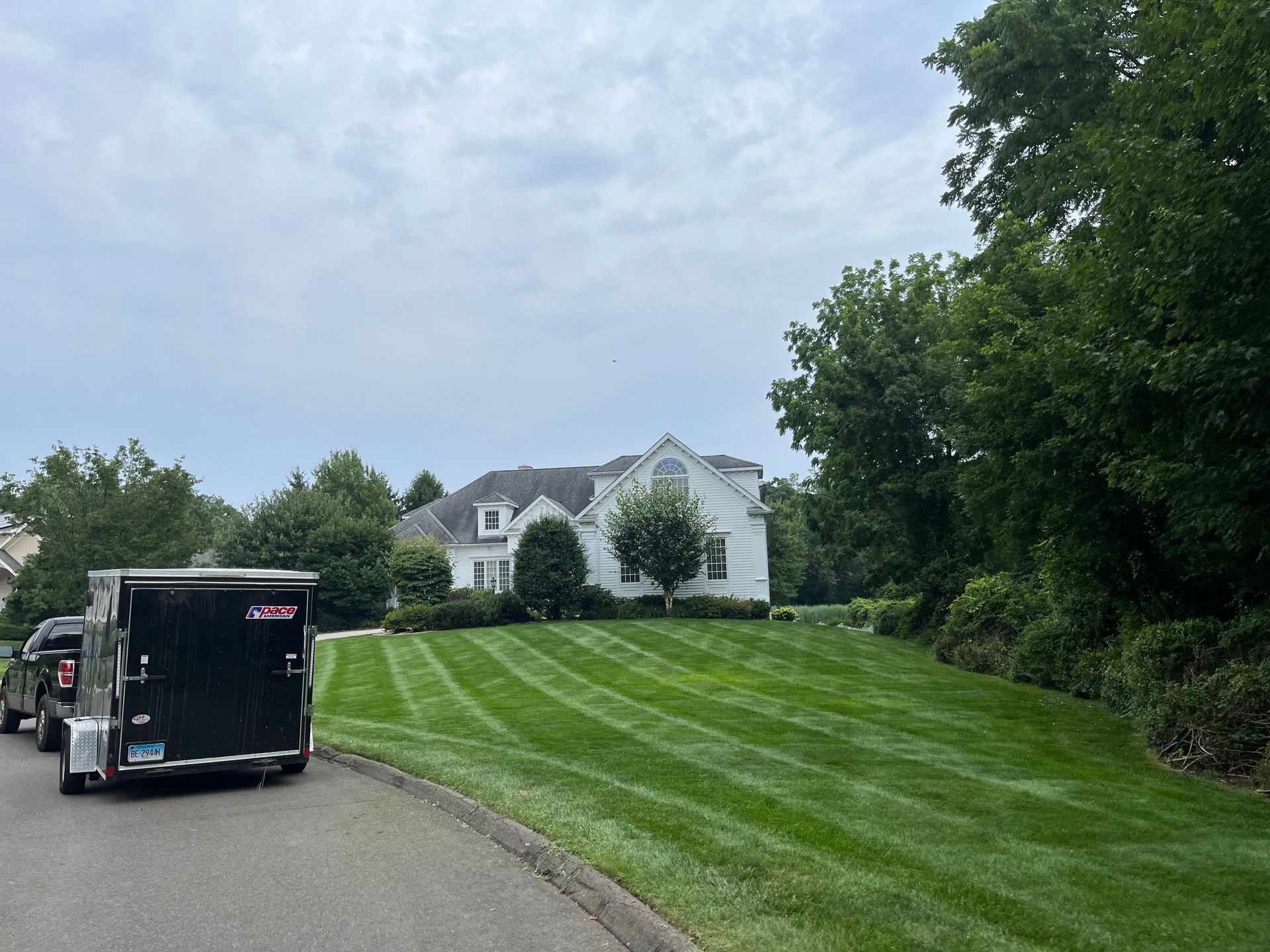 A trailer is parked on the side of the road in front of a house.