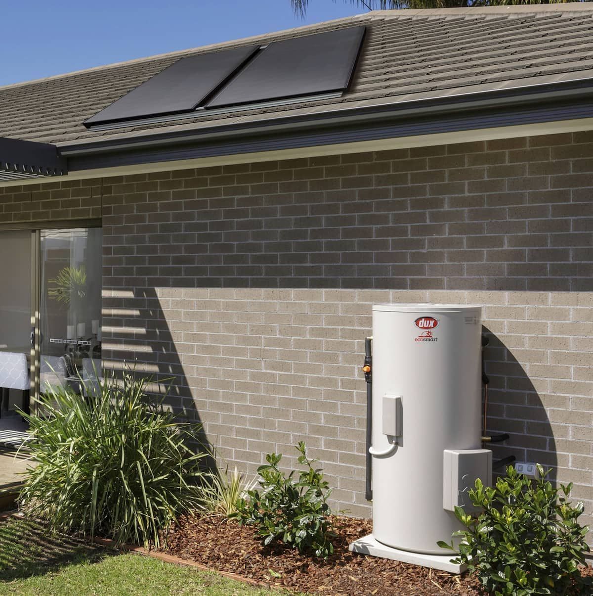 Solar Water Heater Beside a Brick House With a Rooftop Solar Panel — Forster Hotwater in Forster, NSW