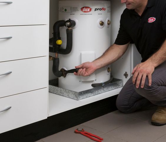 Technician Kneeling Beside White Water Heater — Forster Hotwater in Nabiac, NSW