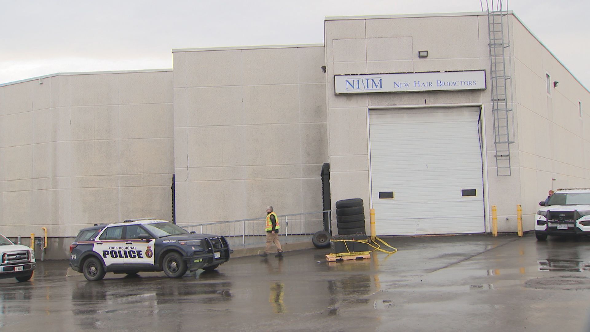 A police officer is standing in front of a house under construction