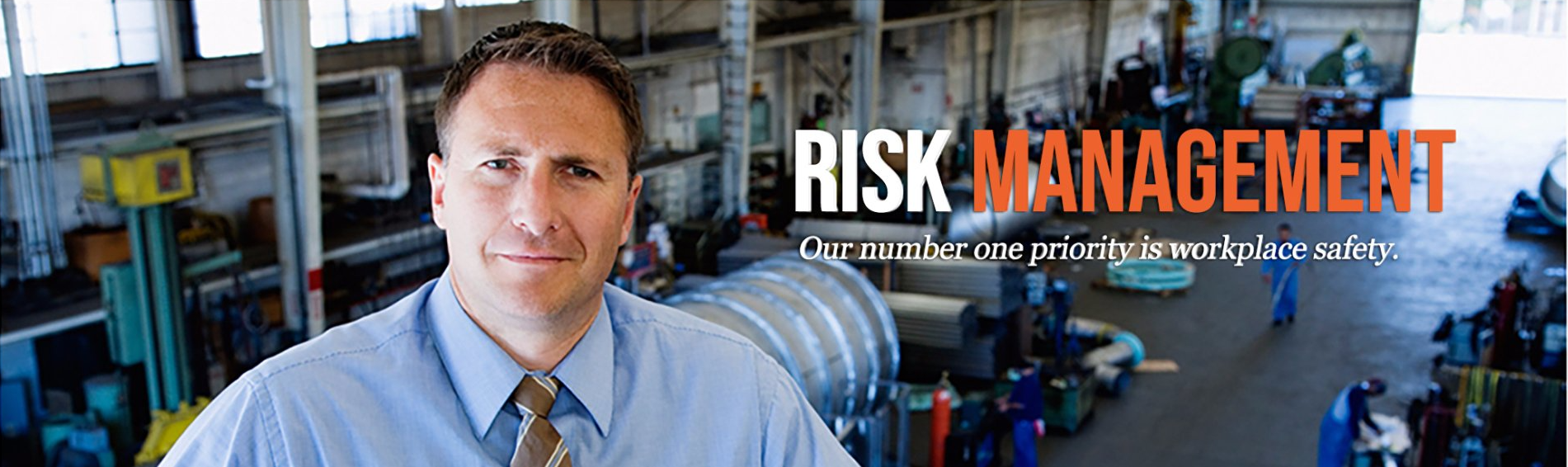 A man in a blue shirt and tie is standing in a factory.