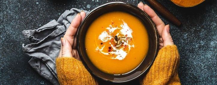 A person is holding a bowl of soup in their hands.