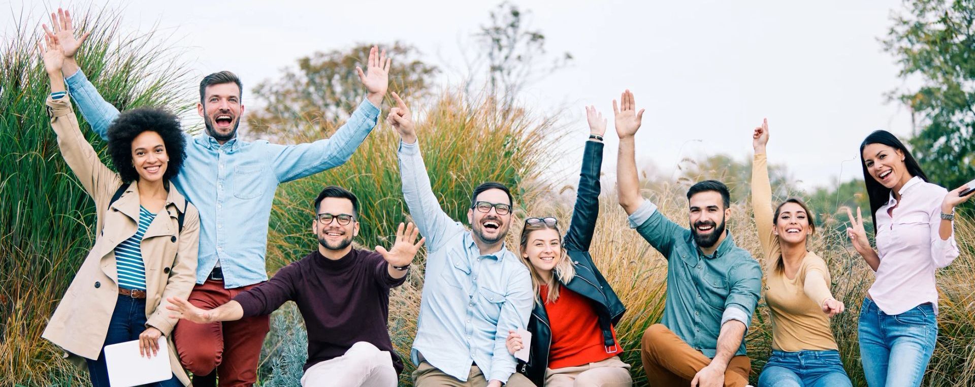 A group of people are standing in a field with their arms in the air.