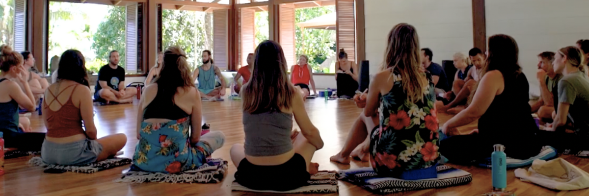 A group of people are sitting in a circle on the floor in a room.