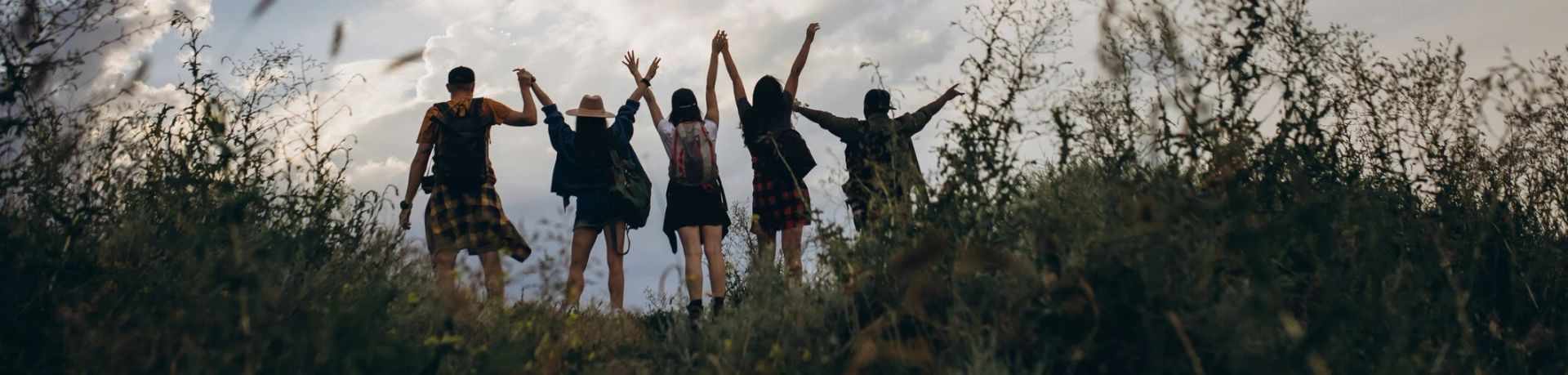 A group of people are standing in a field with their arms in the air.