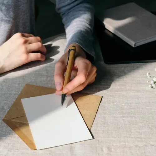 A person is writing on a piece of paper with a pen