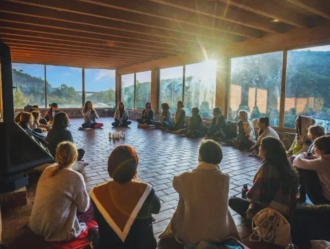 A group of people are sitting in a circle on the floor in a room.