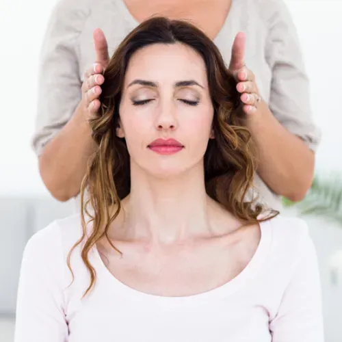 A woman is getting a massage from another woman with her eyes closed.