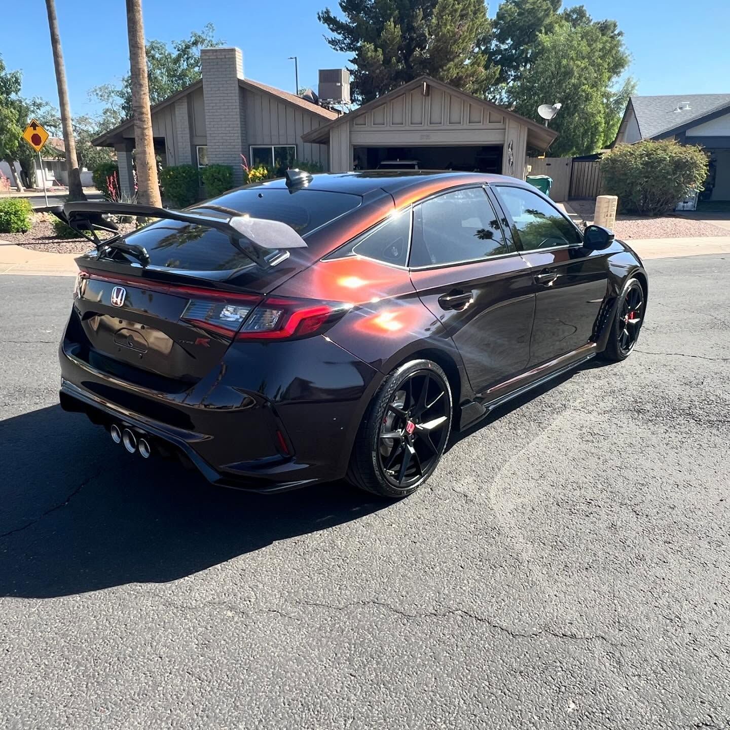 Brown sporty Honda Civic hatchback parked on a paved residential street.
