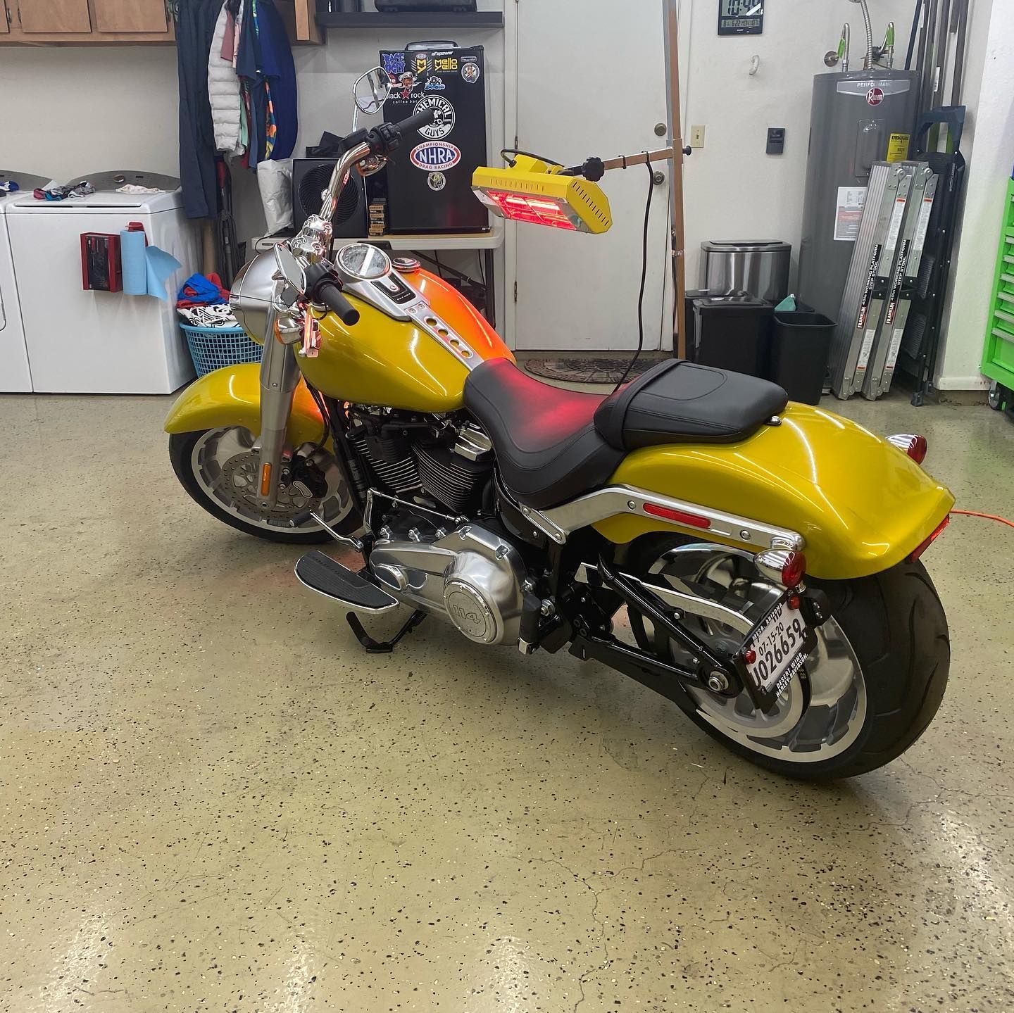 Yellow and orange motorcycle parked in a garage with a speckled floor.
