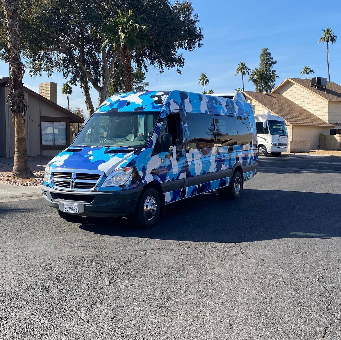 Blue camouflage Dodge van parked on street, residential neighborhood.