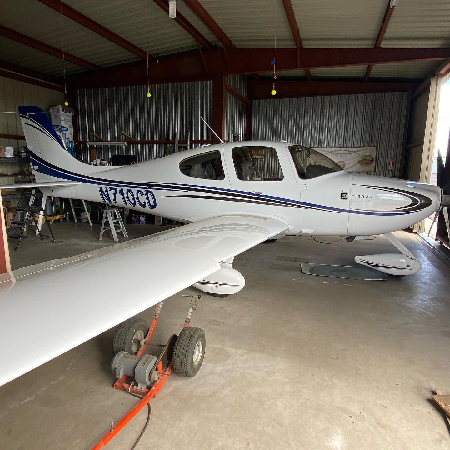 White and blue Cirrus SR22 airplane in a hangar, tail number N710CD.