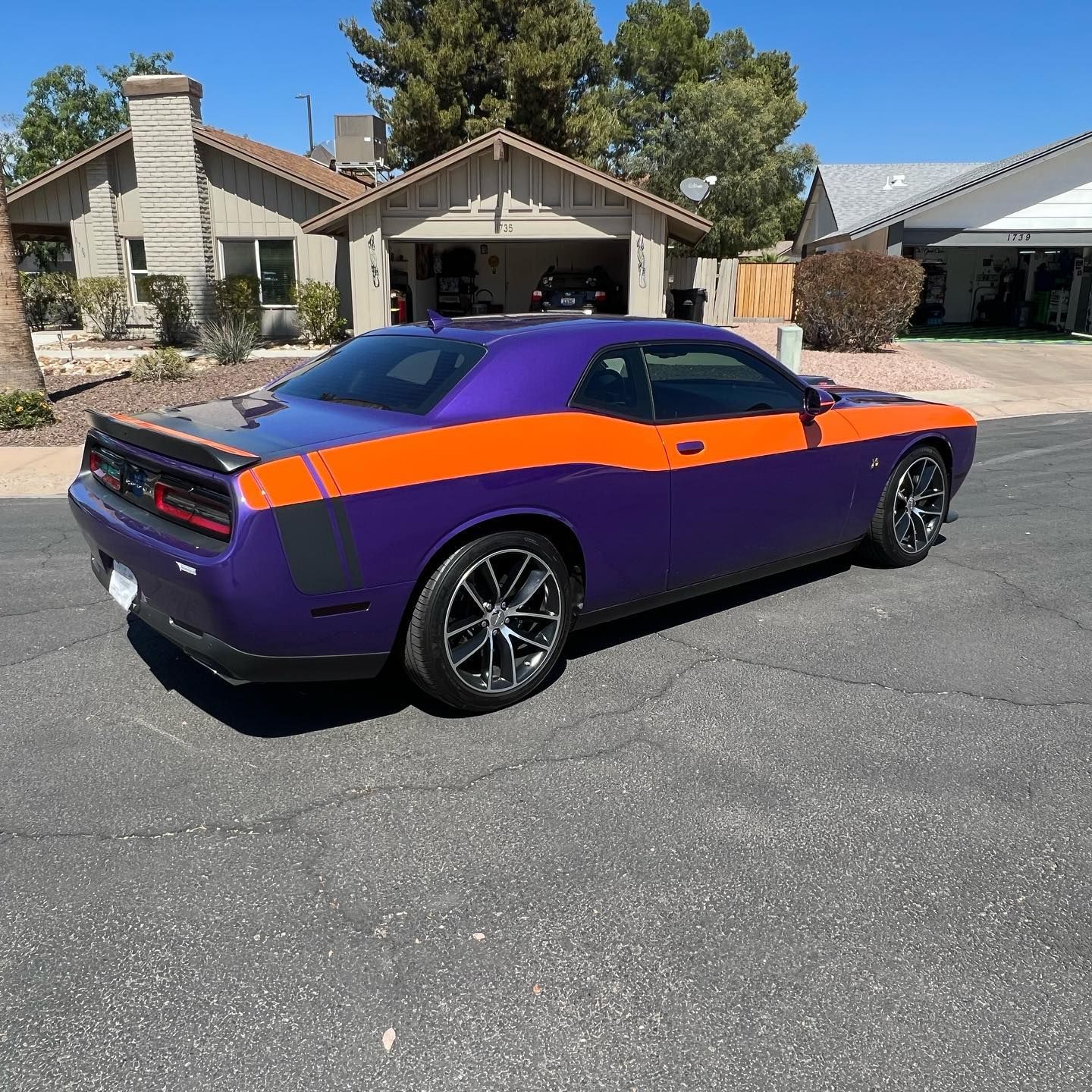 Purple and orange Dodge Challenger parked on a residential street.