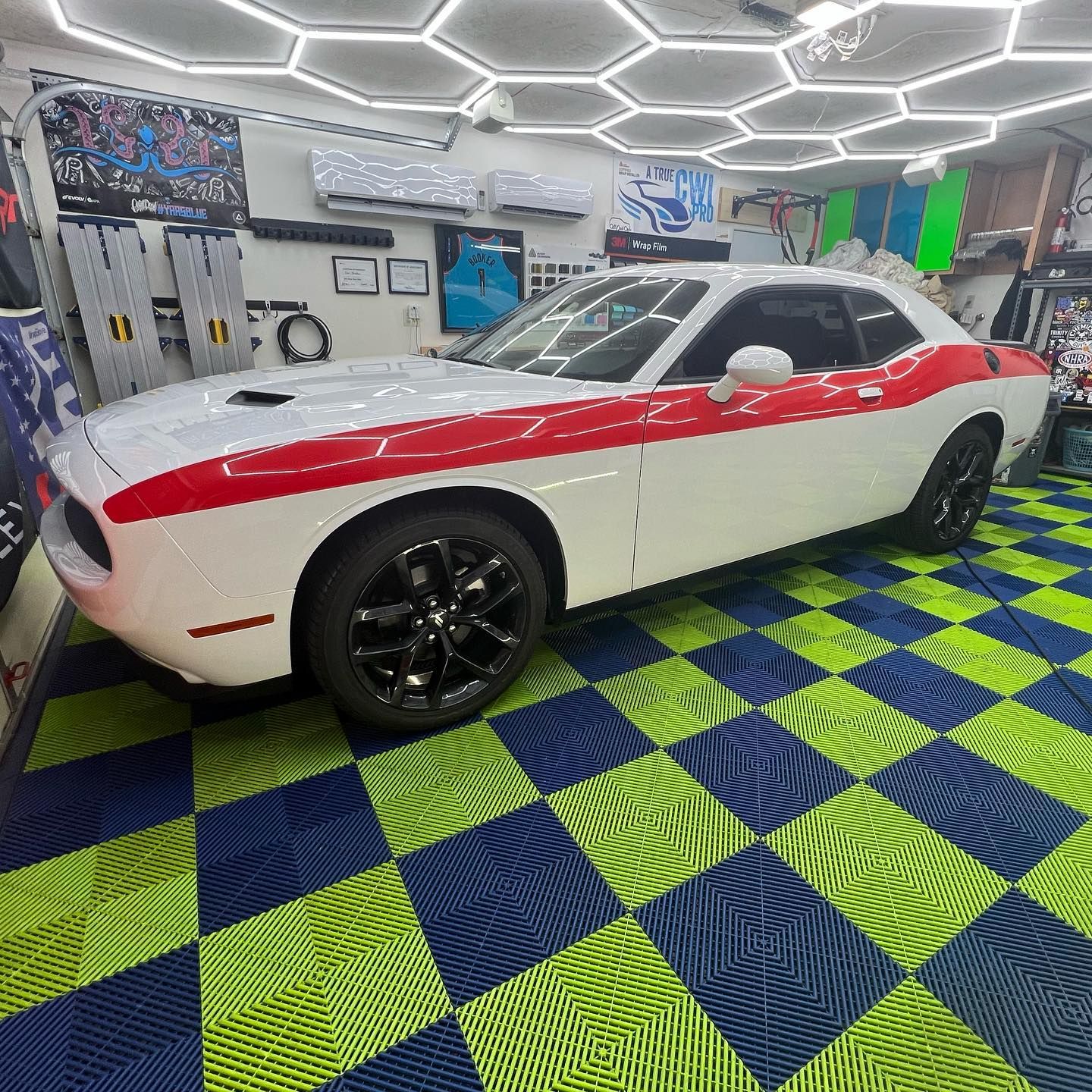 White and red Dodge Challenger in a garage with checkered floor.
