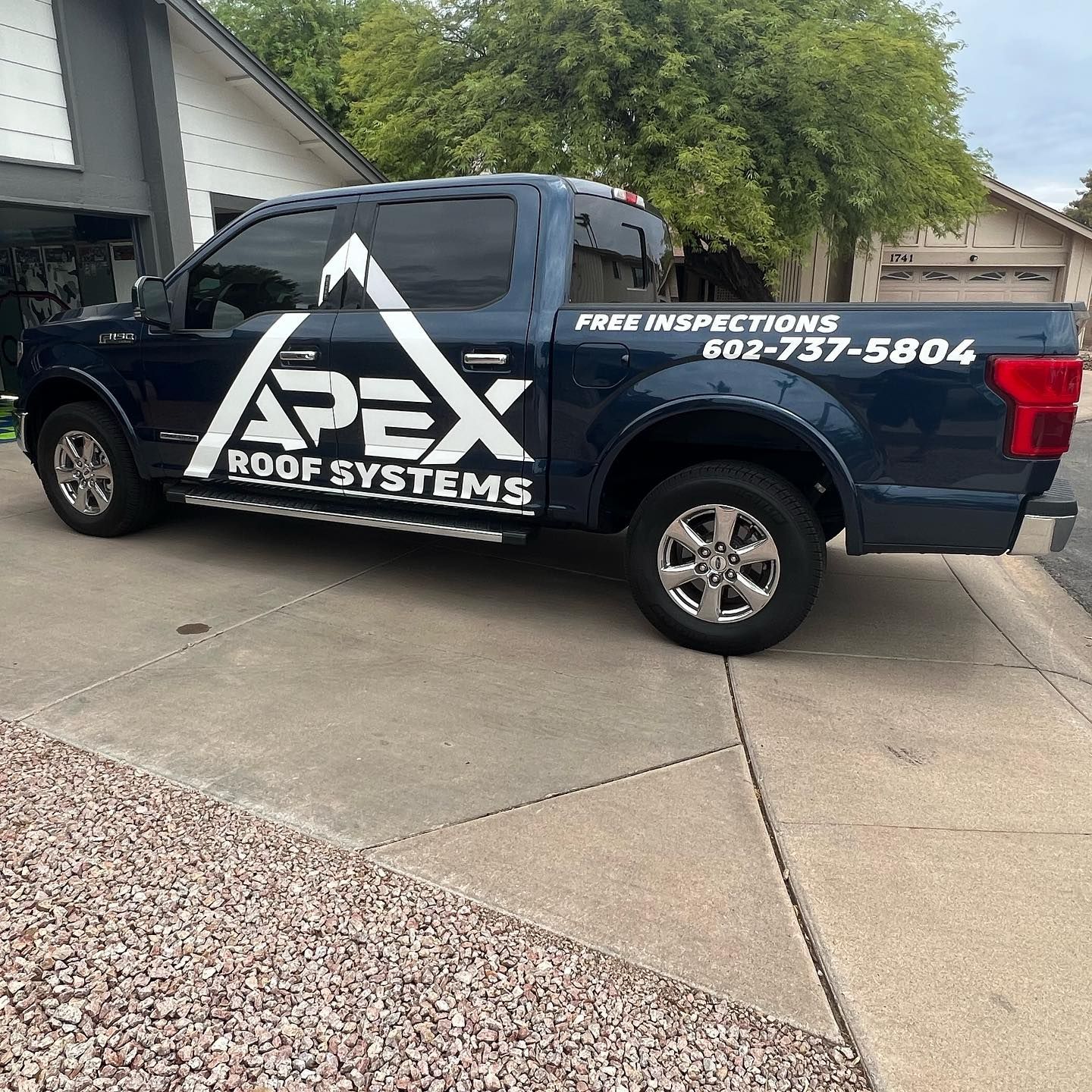 Blue Apex Roof Systems truck parked on a driveway with business logo and phone number.