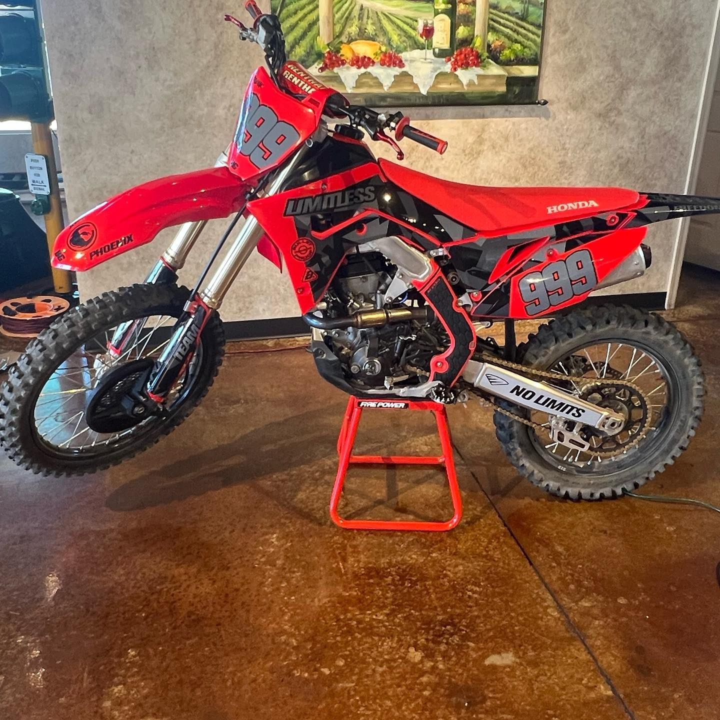 Red and black Honda dirt bike on a red stand, indoors. Number 98 on the front and sides.